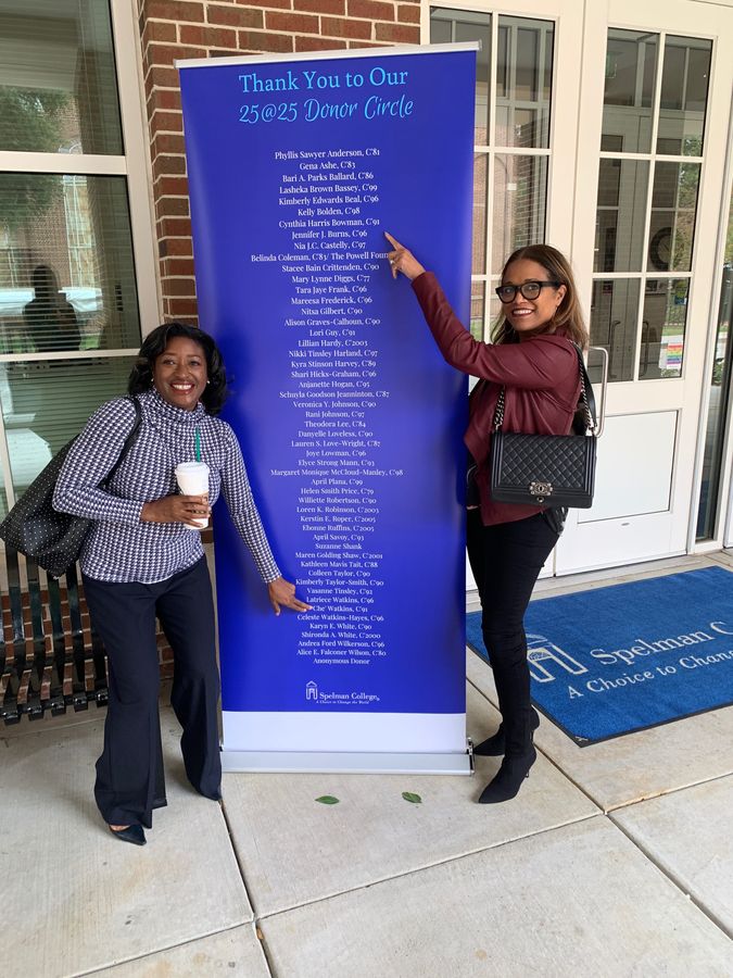 Two women pointing to names on Spelman Collegeβs 25@25 Donor Circle banner, which lists Cynthia Harris Bowman, Cβ91