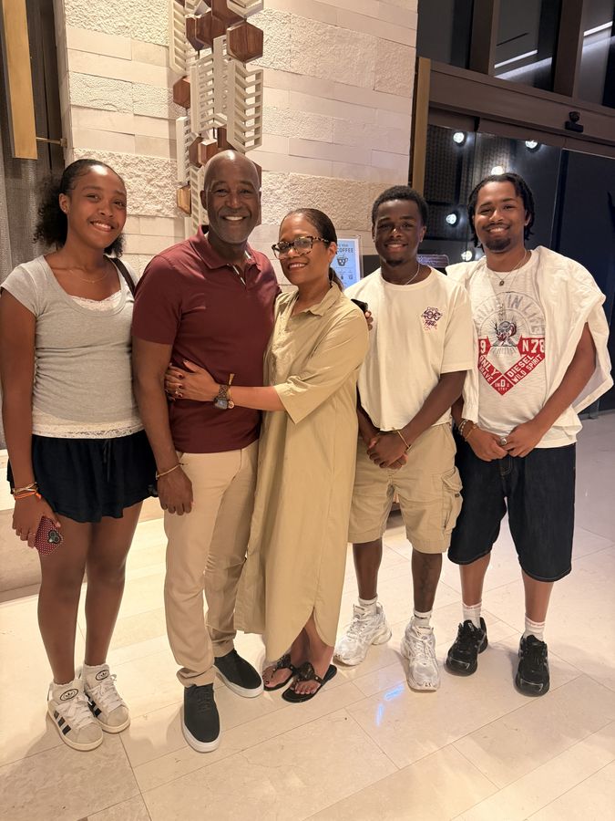 A family of five smiling together in a hotel lobby